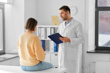 medicine, healthcare and people concept - male doctor with clipboard and female patient having...