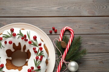 Flat lay composition with traditional Christmas cake and decorations on wooden table, space for text