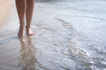 Woman walking through water on seashore, closeup of legs