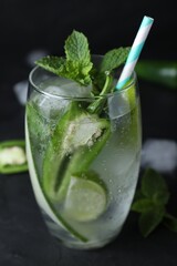 Spicy cocktail with jalapeno, cucumber, lime and mint on black table, closeup