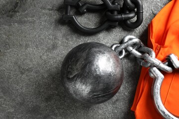 Prisoner ball with chain and jail clothes on grey table, flat lay