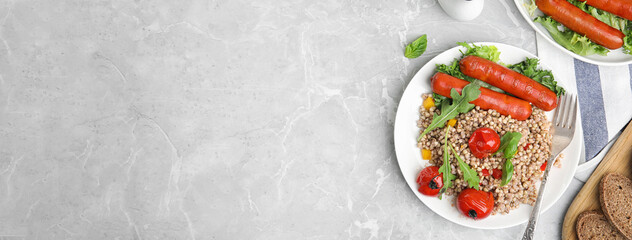 Tasty buckwheat porridge and sausages on light grey marble table, flat lay with space for text. Banner design