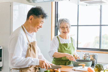 家で一緒に料理を作る笑顔の日本人老夫婦（高齢者）

