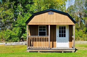 American style wooded shed, with porch. A shed is typically simple, single-story roofed structure in a back garden or on an allotment that is used for storage, hobbies, or as a workshop. Exterior view