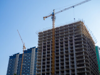 Fototapeta na wymiar High-rise construction. Skyscraper under construction. Housing frame. Multi-apartment housing. Building cranes. New area.