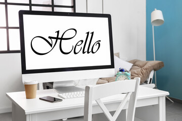 Modern computer with word HELLO on screen in room