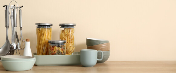 Naklejka na ściany i meble Interior of stylish kitchen with dinnerware, jars of pasta and utensils on counter