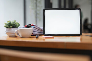 Creative workspace with blank screen digital tablet and stack of document on wooden table.