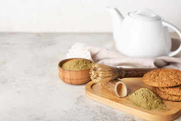 Wooden board with hojicha powder, cookies and chasen on light background