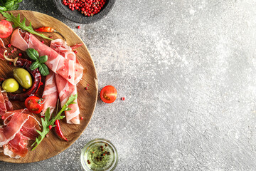 Wooden plate with delicious jamon on grunge background