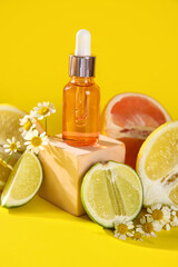 Composition with bottle of essential oil, citrus fruits and chamomile flowers on yellow background, closeup