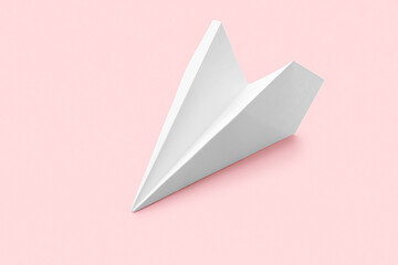 Naklejka premium White paper airplane on a soft pink background, communication, travel, and childhood dreams