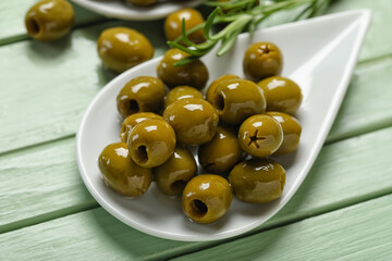 Plate of delicious green olives on color wooden background, closeup