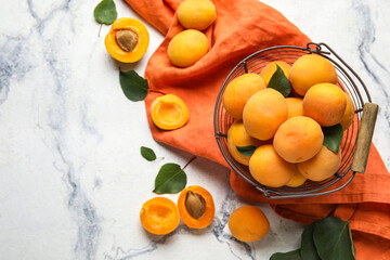 Composition with basket of ripe apricots on light background