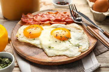 Plate of tasty fried eggs with bacon on wooden table, closeup