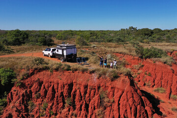 Aerial landscape view of happy Australian family waving hellon beside a car and caravan