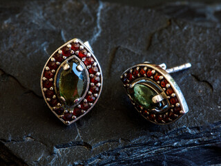 Women's earrings in eye shape with Czech red garnet and green moldavit or vltavin gemstone on black...