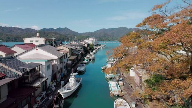 ドローンで空撮された、京都府舞鶴市の「吉原入江」の風景。水路に並ぶ漁船と民家、背景の山々までを見渡せる、ノスタルジックな漁師町の全景。観光PR、地域紹介、日本の港町の魅力を伝える広告・映像素材に。 | Aerial view of Yoshiwara Inlet in Maizuru, Kyoto.