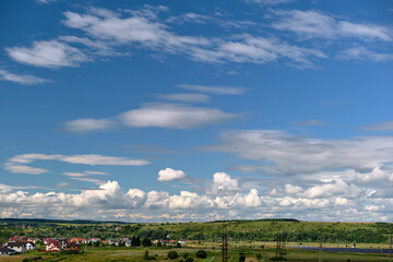 Bright landscape of white puffy cumulus clouds on blue clear sky over rural area