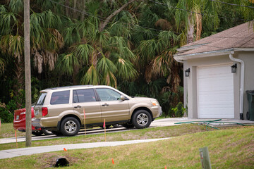 Car parked in front of wide garage double door on concrete driveway of new modern american house