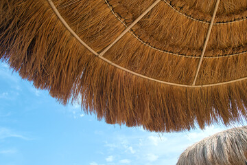 Close up detail of yellow straw roof against blue sky