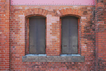 Fototapeta na wymiar 古い煉瓦の建物と鉄の扉で蓋をした二つの窓