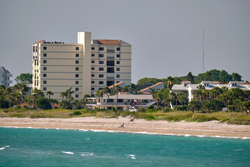 Resort beach with white sand, blue water, tall hotel buildings. Happy people sunbathing and swimming in ocean