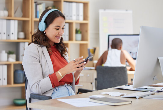 Phone, music headphones and office computer for woman in creative startup company with team worker. Smile, happy and cool brand designer listening to radio while planning social media design schedule