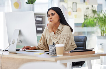 Thinking, attention and business woman on computer working by desk in design company office...