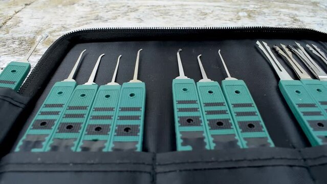 Lockpicking tools kit in a pouch on white wood surface.
Lockpick tools in a pouch kit opened spread on a white table. Camera sliding left to right.
