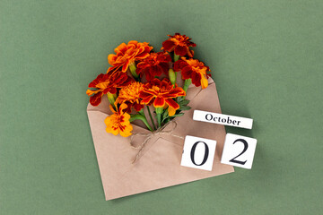 October 2. Bouquet of orange flower in craft envelope and calendar date on green background. Minimal concept Hello fall. Template for your design, greeting card