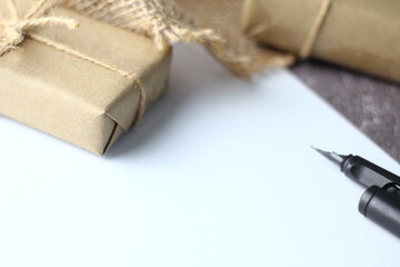 Holidays Gifts. Christmas and New Year..Gift box wrapped in brown paper, pine cones and white paper and pens placed on the table, copy space.