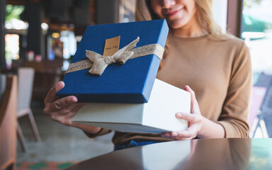 Closeup image of a young woman receiving and opening a red present box