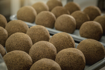 Cheese balls sprinkled with black pepper lie in a row . The production process of spicy Belper knolle cheese