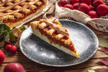 Appetizing homemade pie on a wooden table with garden apples, cinnamon and autumn leaves. Concept of a cozy atmosphere and autumn mood