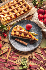 Appetizing homemade pie on a wooden table with garden apples, cinnamon and autumn leaves. Concept of a cozy atmosphere and autumn mood