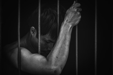 hand man hold steel in jail on black background.concept for prisoner,sadness,detain,erroneousness.black and white tone