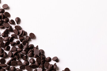 Overhead view of fresh chocolate chips scattered by copy space on white background