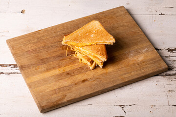 High angle view of fresh cheese sandwich served on wooden brown serving board over white table