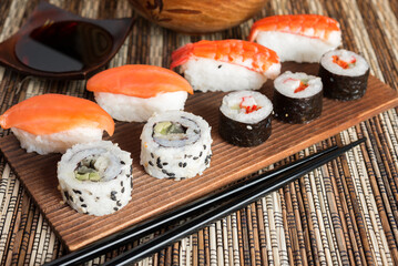 Sushi Set nigiri shrimp and salmon and sushi california rolls with avocado and maki with carrot, on wood,top view, soy sauce