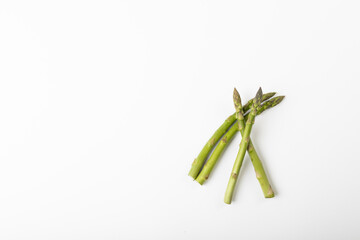 Directly above view of raw green asparagus against white background with copy space