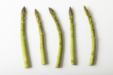 Overhead view of raw asparagus arranged side by side with copy space on white background - Powered by Adobe
