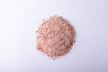 Small heap of pink rock salt on white background with copy space