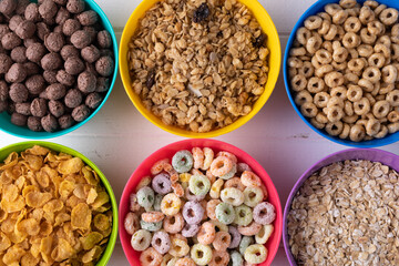 Full frame shot of various breakfast cereals in colorful bowls arranged on table with copy space