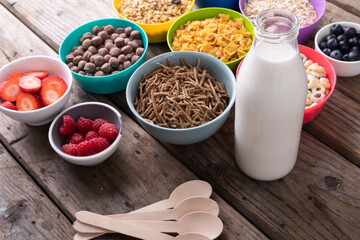 High angle view of various cereal bowls with milk and berry fruits arranged on table