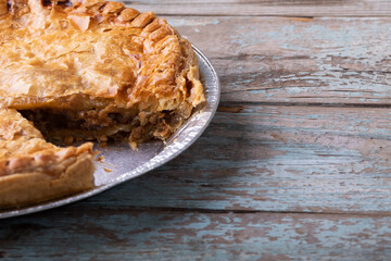 Close-up of baked stuffed pie sliced in plate on wooden table with blank space