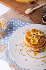 High angle view of delicious pancakes with banana slices, oats and honey in plate over napkins
