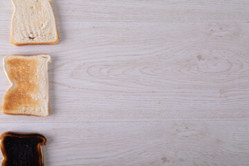 Directly above shot of toasted and burnt bread slices in a row on table with copy space - Powered by Adobe