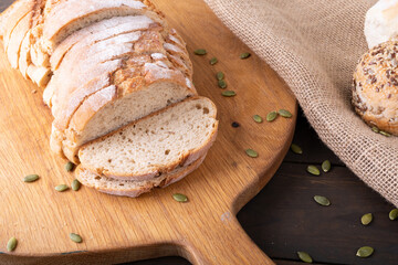 High angle close-up of sliced bread loaf with seeds on wooden serving board