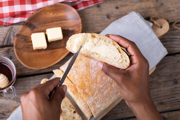 Cropped hands of african american man applying butter on bread slice
